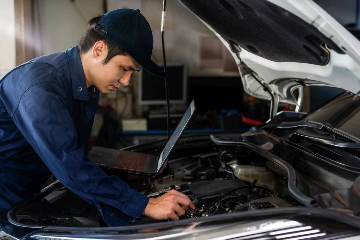 male mechanic using a laptop while repairing car in auto service